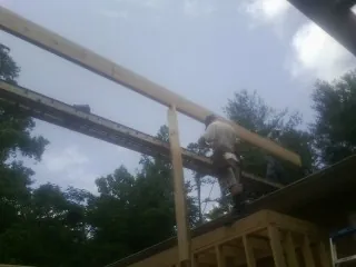 Carpenter setting a ridge beam over a new addition frame — Ice Dam Removal by Roofing Brothers in Thurmond