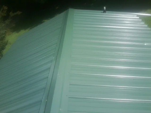 New green metal panels meeting at the ridge of a roof — Flat Roof Repair work by our crew in Thurmond