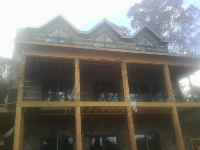Dormers and porch framing on a large log home under construction — Roof Coating work by our crew in Thurmond
