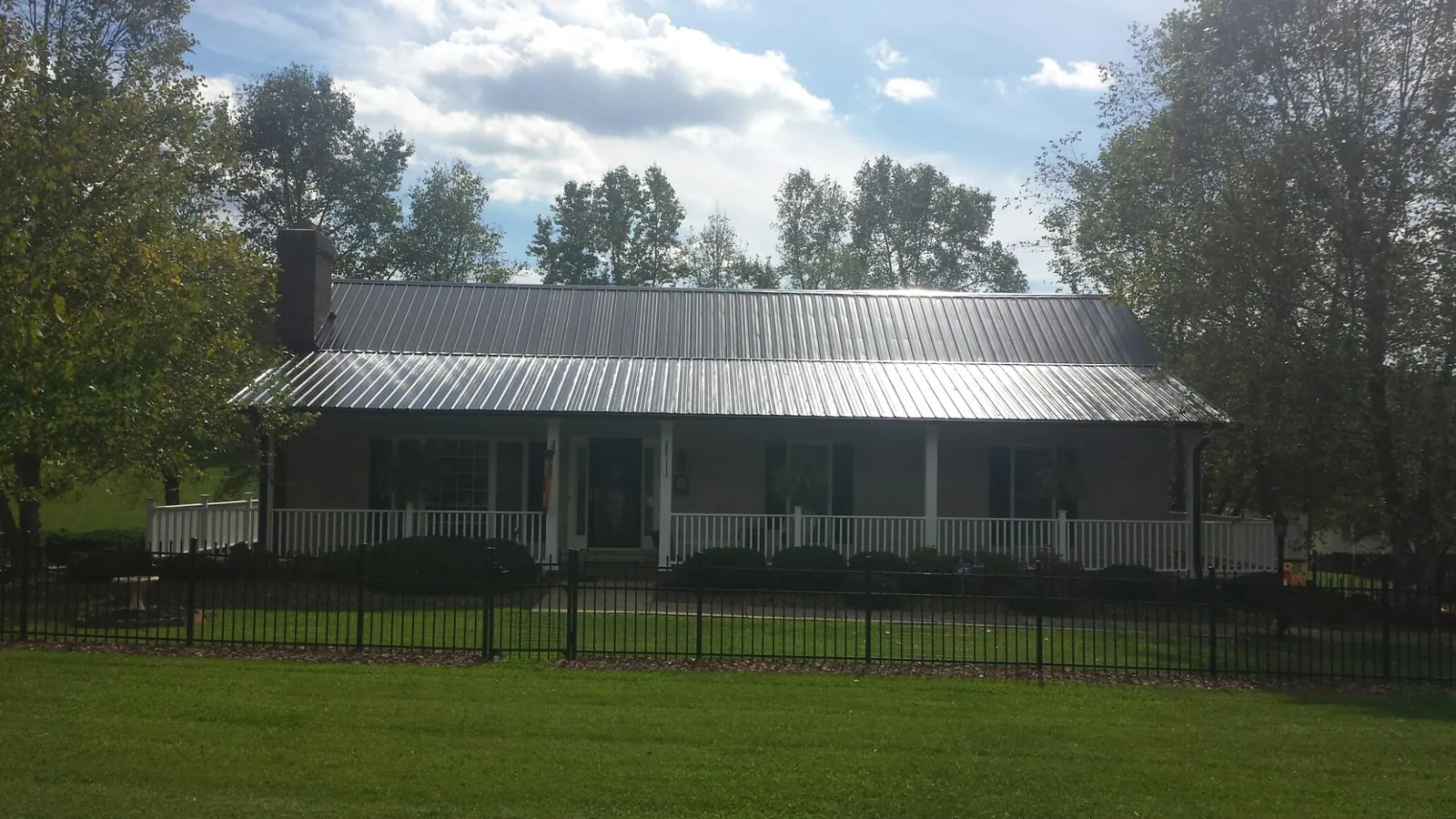 Gray metal roof on a brick ranch with a full width front porch — Gutter Guard Installation work by our crew in Thurmond