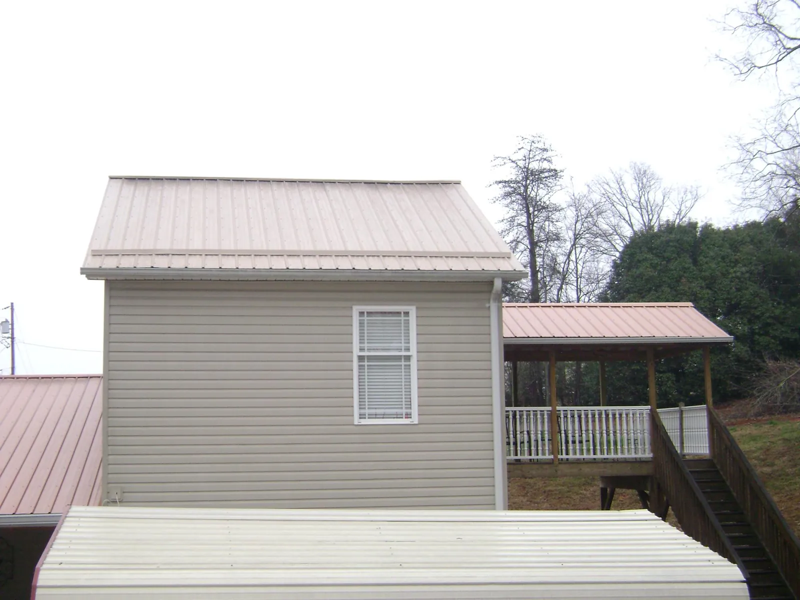 Tan metal roofs on a two story addition and attached porch, from a Roof Replacement job in Thurmond