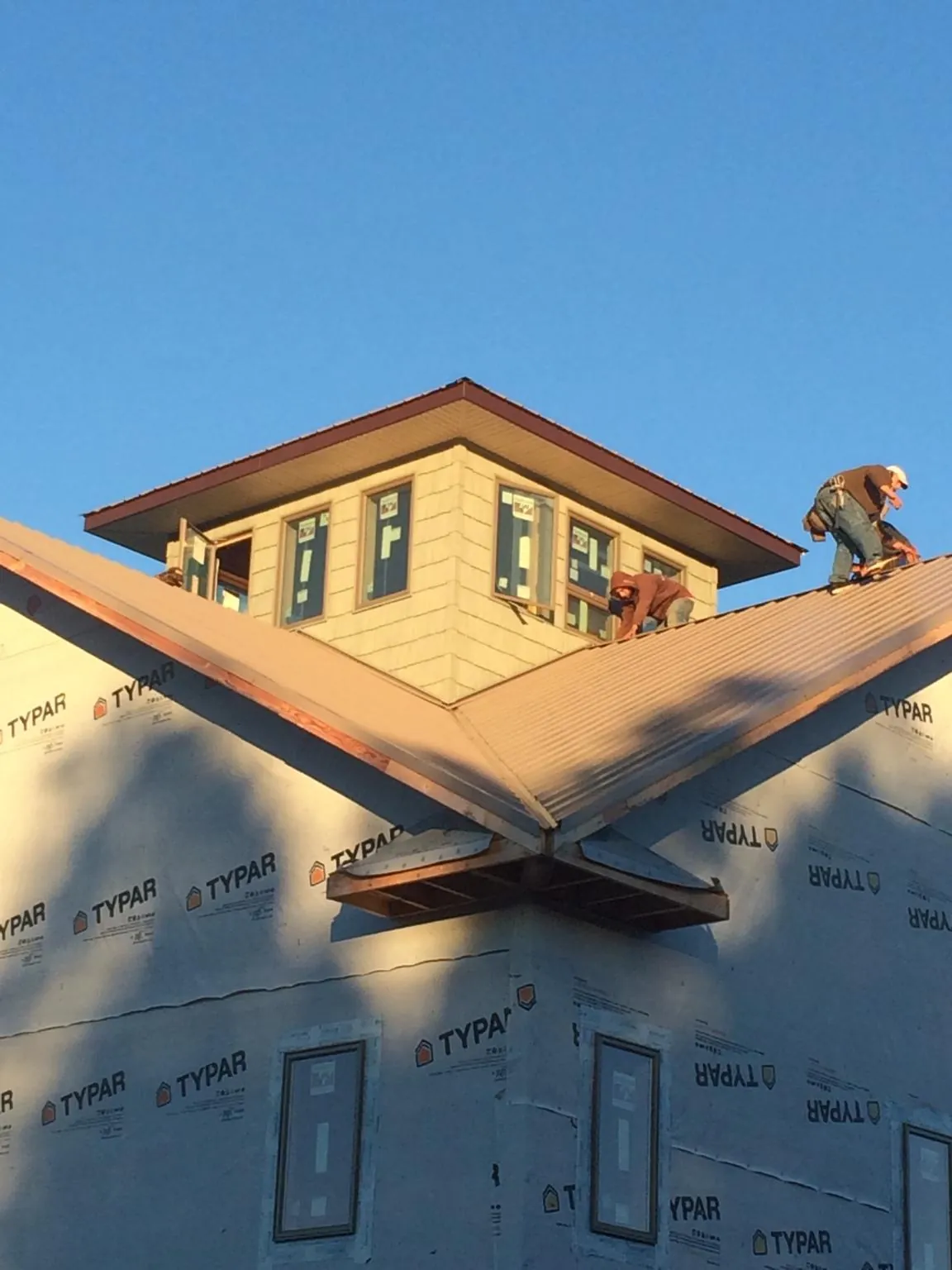 Roofers working around a rooftop cupola on a new metal roof at sunset — Roof Waterproofing in Thurmond by Roofing Brothers